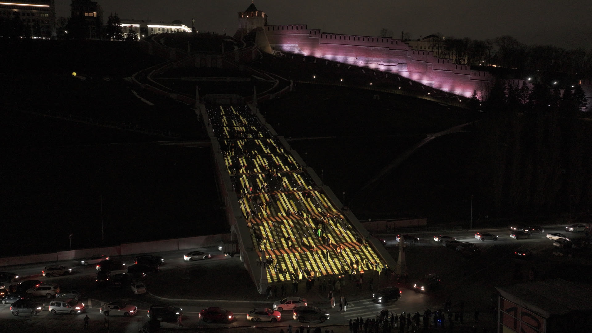 Aerial view of Ascent projection mapping on the Chkalov Staircase in Nizhny Novgorod at night for Intervals festival, golden light patterns climbing the steps with the kremlin wall lit pink above